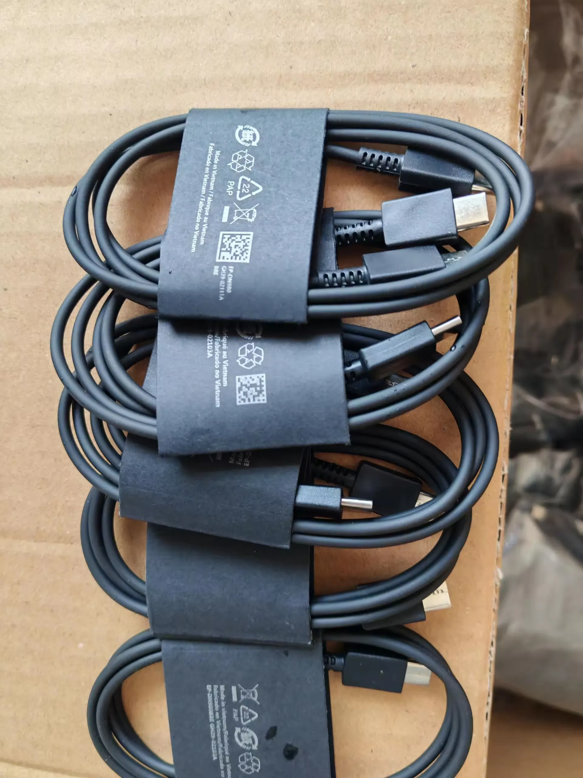Black Type-C to Type-C charging cables coiled with black paper sleeves in a carton