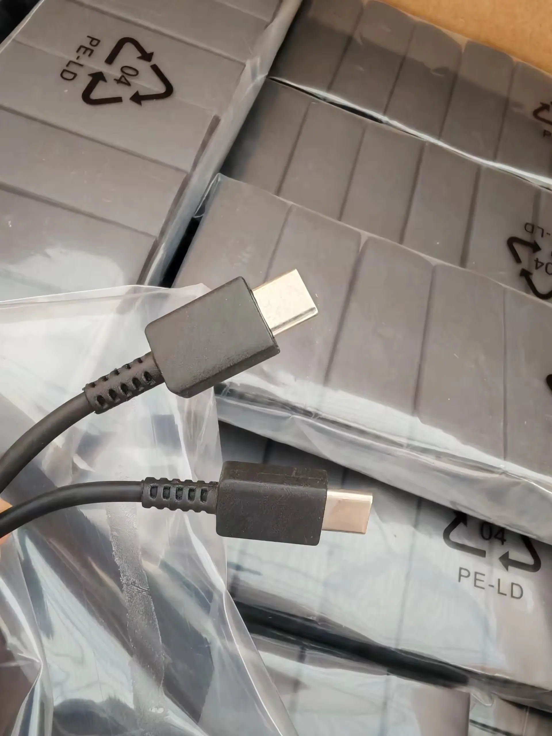 Close-up of black Type-C to Type-C cable connectors with carton packaging in the background